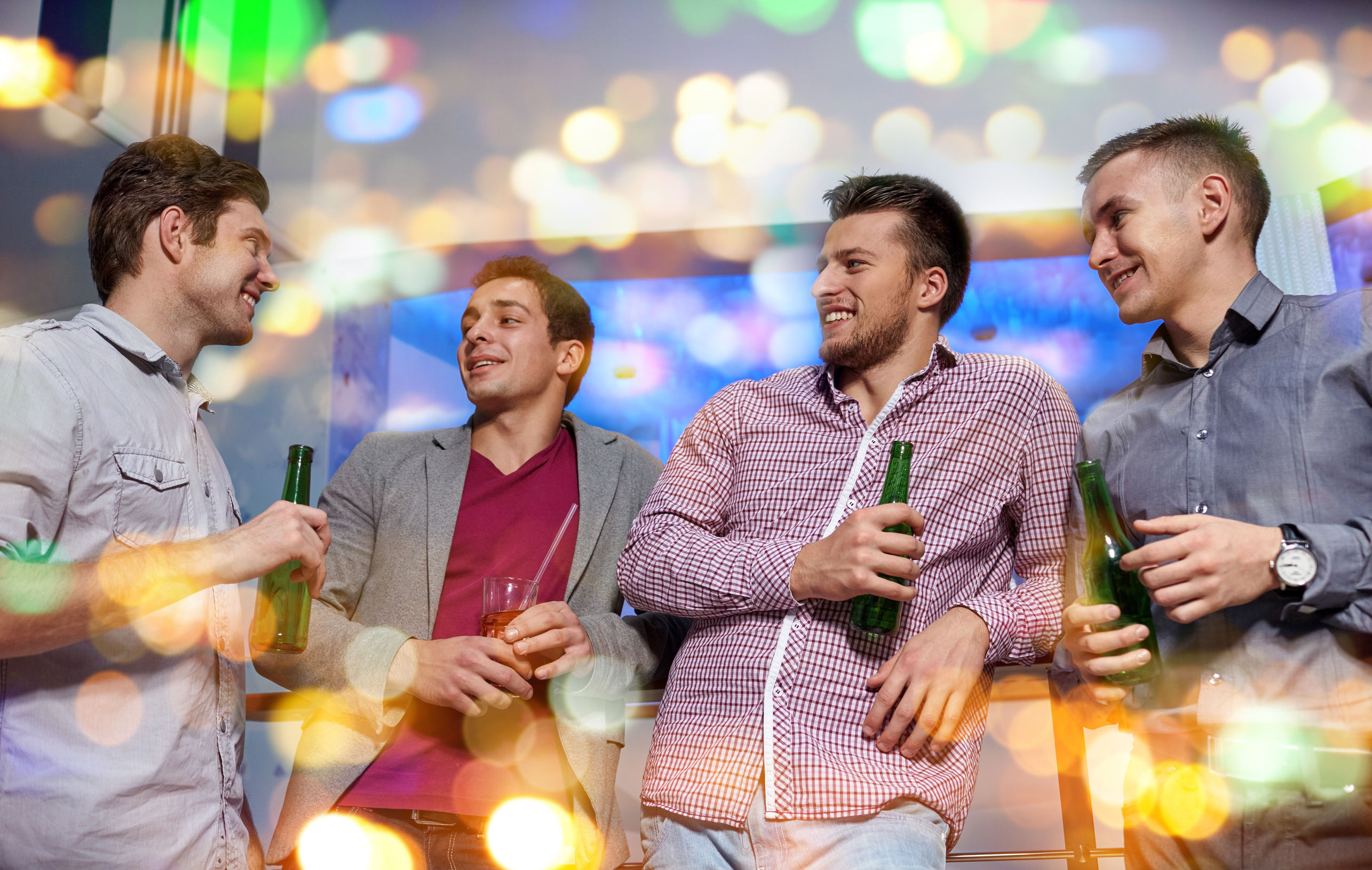 48776354 - nightlife, party, friendship, leisure and people concept - group of smiling male friends with beer bottles drinking in nightclub